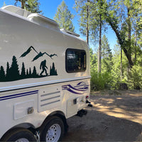 a white trailer parked in a forest with trees